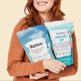 A person holding two packets labeled 'binto. fertility kit' with a smiling face, one packet is white and the other is blue.